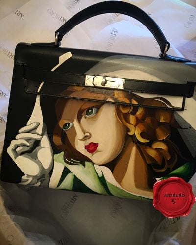 ARTBURO Personalization : Hand Painted HERMÈS Vintage Kelly Bag, Girl in Green with Gloves by Tamara de Lempicka, (1929). "Art Deco Collection by ARTBURO" for Angelika Ivanc.  АРТБЮРО Персонализация : Ручная Роспись HERMÈS Vintage Kelly Bag, Девушка с перчатками Тамара де Лемпицка, (1929). Коллекция АРТБЮРО "Арт-Деко". Exceptional HERMÈS bag.  Artist:Tamara De Lempicka Created:1931 Dimensions (cm):45.5 x 61.5 Format:Oil on plywood Location:Musée national d'art moderne, Paris, France   Perhaps Tamara De Lempicka’s most famous painting, ‘Girl in Green with Gloves’, has been an icon to her artistic style and work throughout her career. Painted in 1929, the ‘Girl in Green with Gloves’ displays a beautiful young woman wearing a flimsy green dress, white gloves, and a large, white hat. The sharp-edged form combined with the bold use of color render the whole strongly dimensional and modern. It appears that the sleek feminine figure with curvaceous lines is holding on to her hat in order to avoid losing it in the breeze, De Lempicka undoubtedly masters the effect of a wind blowing through the painting. A slight sense of eroticism is established by having the dress cling to her body, revealing her breasts and navel through the fabric.